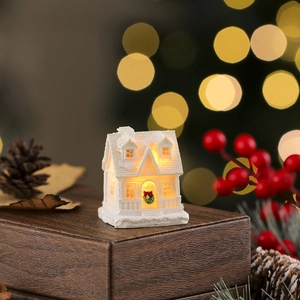 Detail of warm white LED Christmas resin house with snowy texture and holiday wreath