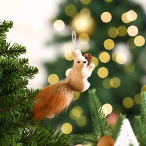 Close-up of a Christmas squirrel ornament with fur tail and pine cone on a pine tree