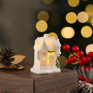 Macro detail of white resin house with snow texture and warm LED glowing inside