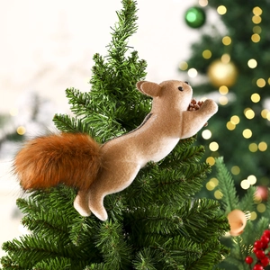 Detail of a fluffy faux fur squirrel tree ornament with a pinecone on green branches