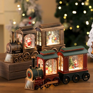 Close-up of vintage bronze and red Christmas train music boxes with swirling snow and lights