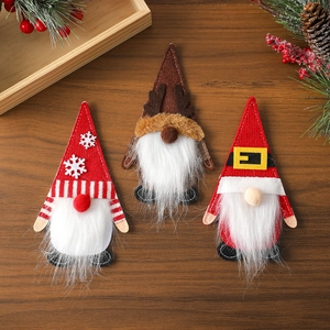 Three-piece Christmas gnome cutlery set and hanging ornaments on dark wood surface