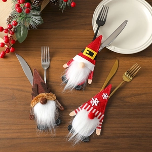 Close-up of Christmas gnome felt cutlery holders on wooden table with holiday decor