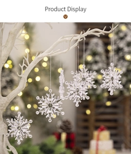 Close-up of clear acrylic snowflake ornaments hanging on a tree with festive warm lighting
