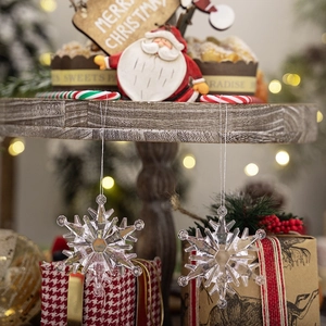 Close-up of clear acrylic snowflake ornaments hanging with warm festive bokeh lights