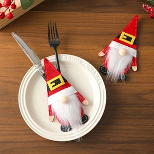 Close-up of red felt gnome cutlery holder with white beard on festive dinner table