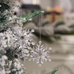Macro shot of 6pcs transparent acrylic snowflake ornaments hanging on snowy pine branches