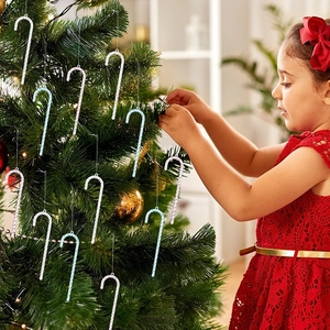 Little girl hanging sparkly blue and silver candy cane ornaments on a festive Christmas tree