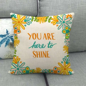 Detail of linen pillow cover featuring You Are Here To Shine quote and floral print