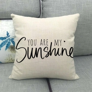 Linen cushion cover with 'YOU ARE MY Sunshine' print on a gray fabric sofa