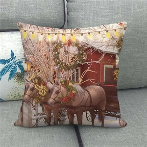 Christmas horse linen pillowcase with winter snow scene and red cottage on a grey sofa