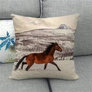 Close-up of linen pillow cover showing a horse in snow on a gray fabric sofa