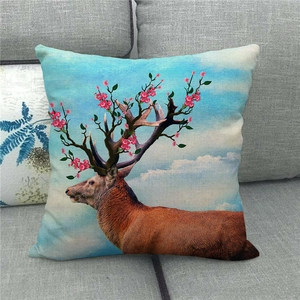 Leinen-Kissenhülle mit floralem Hirsch-Stickerei-Detail auf grauem Stoff-Sofa