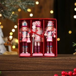 Three pink candy-themed wooden nutcracker soldiers in a red gift box on a festive table