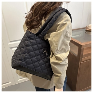 Close-up of black quilted tote bag featuring silver bow detail and leather base