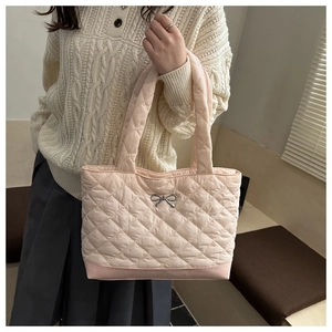 Close-up of pink quilted tote bag showing diamond stitching and silver bow detail