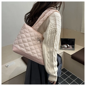 Detailed view of pink quilted tote bag with silver bow ornament and soft padded shoulder strap