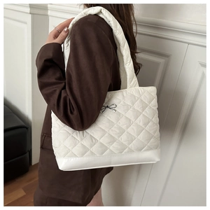 Detail of white quilted nylon tote bag with silver bow charm and reinforced base