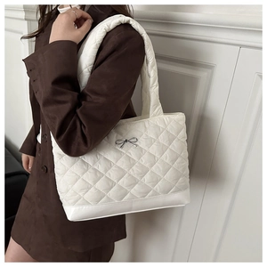 Close-up of white quilted plush tote bag featuring a silver bow-knot metal clasp detail