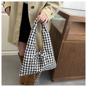 Detail shot of black and white checkered tote bag with bow accent on a model