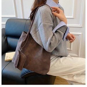 Detail of a dark brown matte leather tote bag with a small matching pouch on shoulder