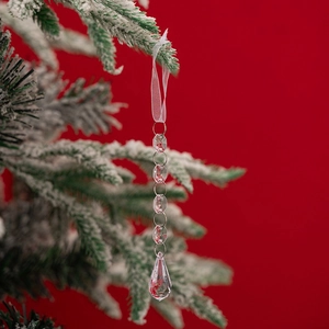 Close-up of clear acrylic icicle hanging on snow-covered Christmas tree branch