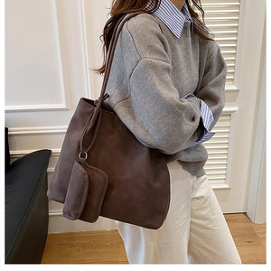 Close-up of deep brown matte leather tote bag with small attached pouch and letter print