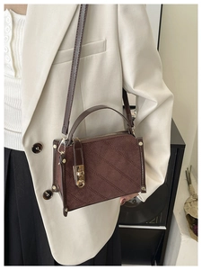 Close-up of diamond-quilted suede crossbody bag with golden twist lock and rivet details