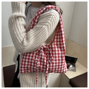 Detail of red and white checkered tote bag with side bow and stylish casual fabric texture