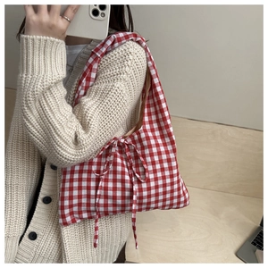 Gros plan détaillé d'un sac cabas en vichy rouge avec un nœud décoratif et cordon de serrage