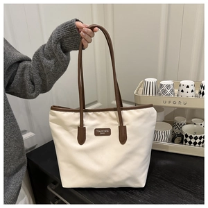 Close-up of minimalist tote bag featuring a leather brand tag and sturdy shoulder straps