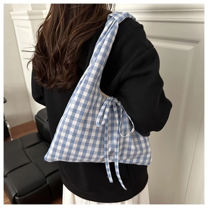 Detail of blue plaid canvas tote bag featuring decorative ribbon bow on the shoulder strap