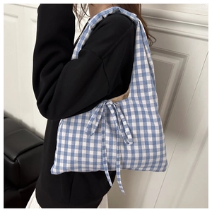 Detail view of blue and white checkered shoulder bag with decorative side bow accents