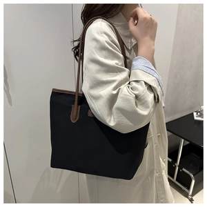 Detail of large tote bag with black canvas and brown leather straps for daily commute