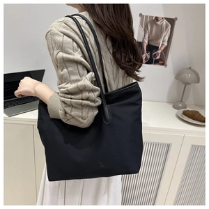 Large black tote bag shown on model shoulder for chic city commute and daily office use