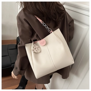 Detail of cream tote bag with pink leather chain strap and cute tiger charm accessory