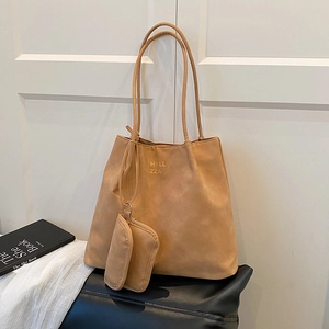 Brown matte leather tote bag set with golden logo and hanging pouch on leather bench