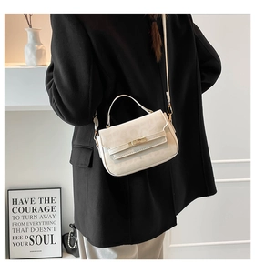 Détail d'un sac bandoulière beige à texture léopard avec fermoir doré sur un manteau noir