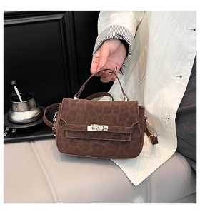 Détail du sac à main léopard marron foncé avec fermoir rotatif doré et texture en suède
