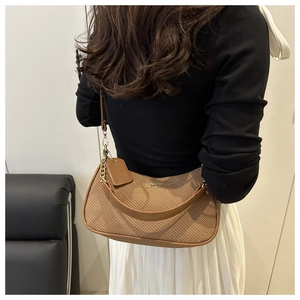 Brown woven hobo bag with leather trim and gold chain detail on model's shoulder