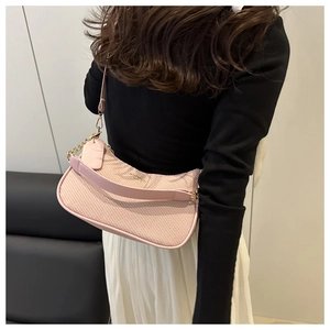 Detail der rosa geflochtenen Umhängetasche mit goldener Kette und minimalistischem Design