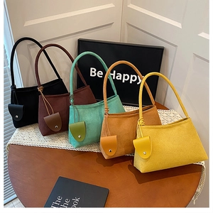 Detail of minimalist suede shoulder bags in five colors with matching charm accessories