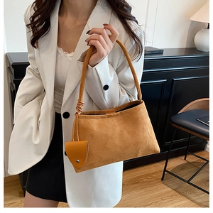Close-up of ginger suede underarm bag with a matching leather mini pouch detail