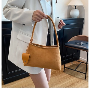 Detail of tan faux suede hobo bag with braided handle and small hanging coin pouch
