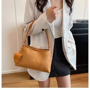 Detail view of mustard yellow suede tote bag with knotted strap and small round coin purse