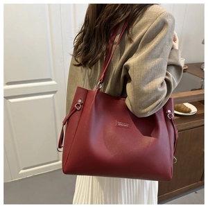 Detail of dark red faux leather tote bag with side drawstring showing stitching and texture