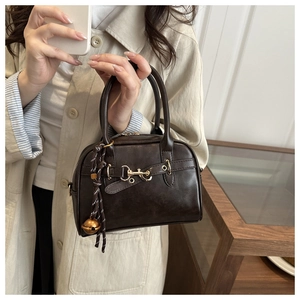 Close-up of vintage dark brown tote bag with gold horsebit detail and bell charm