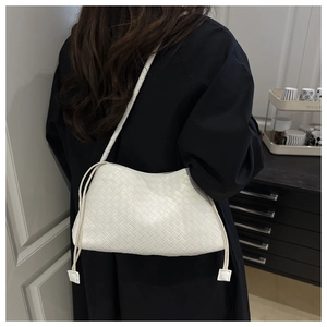 Dettaglio della borsa a tracolla in pelle bianca intrecciata con un elegante trench nero