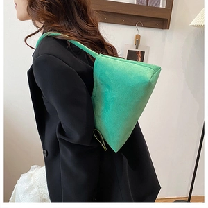 Green suede underarm bag styled with a black blazer for a modern fashion look