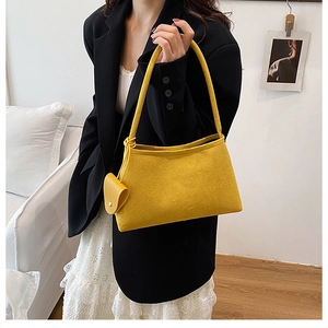 Close-up of bright yellow suede tote bag with matching mini pouch on a female model